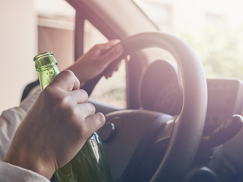 homme tenant une bouteille de biere au volant