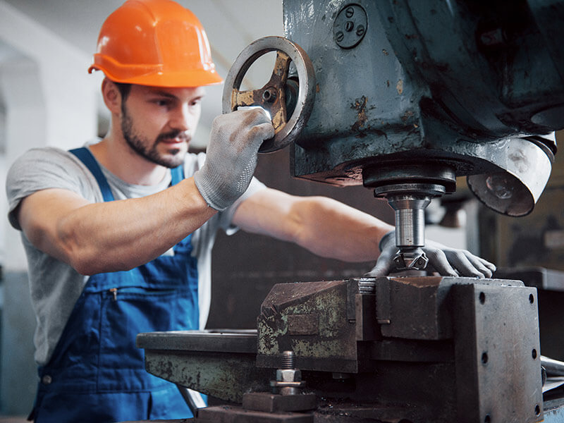 jeune travailleur sur machine portant des gants de protection