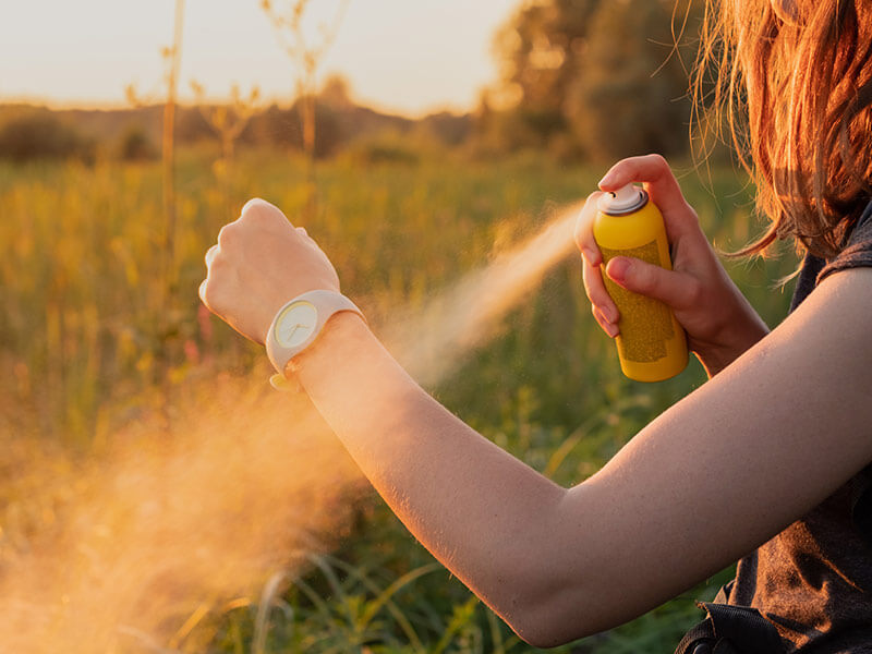 femme se mettant de l'insecticide sur le bras