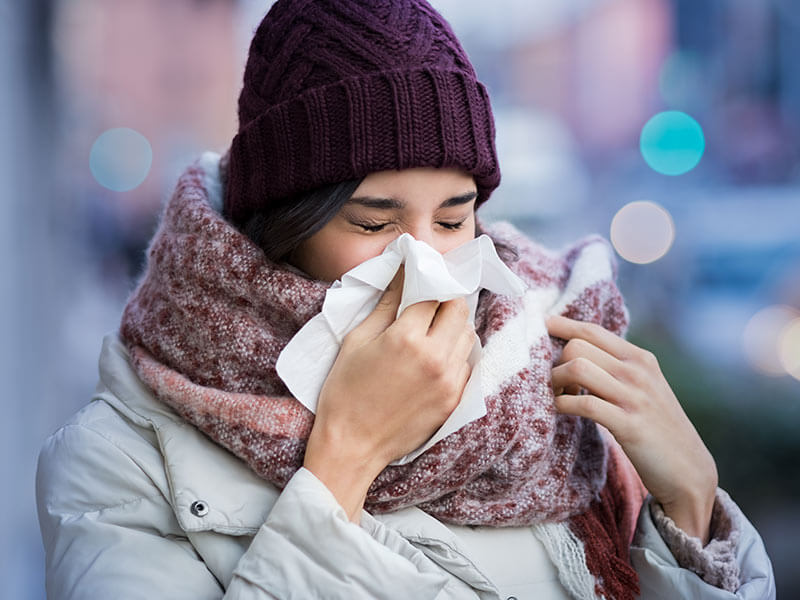 femme enrhumee se mouchant dans le froid de l'hiver